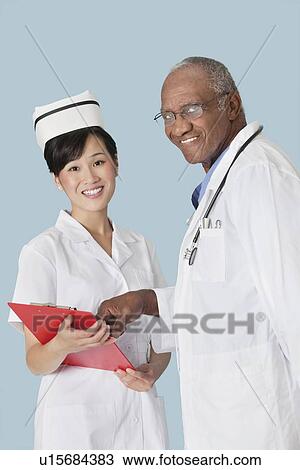 Portrait of happy medical professionals having a discussion over medical report against light blue background View Large Photo Image Stock Image - Portrait of happy medical professionals having a discussion over medical report against light blue background. Fotosearch