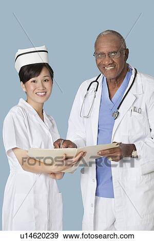 Portrait of happy medical professionals with medical report against light blue background View Large Photo Image Stock Photo - Portrait of happy medical professionals with medical report against light blue background. Fotosearch