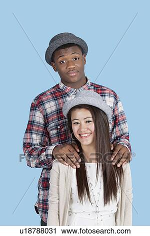 Stock Image - Portrait of happy multi ethnic couple over blue background. Fotosearch