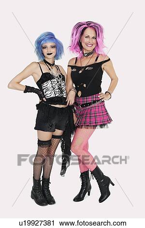 Stock Image - Portrait of happy senior and young punk females standing over gray background. Fotosearch