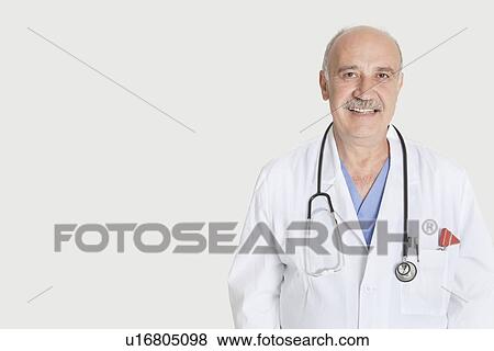 Portrait of happy senior medical practitioner over gray background View Large Photo Image Stock Photo - Portrait of happy senior medical practitioner over gray background. Fotosearch