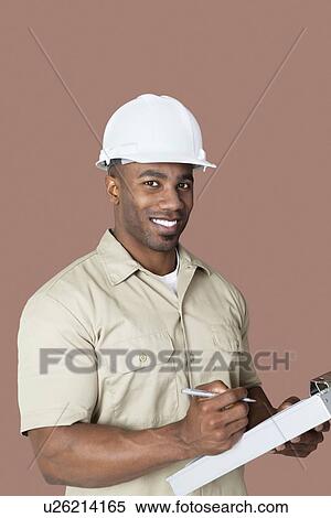 Portrait of happy young African male construction worker holding clipboard over brown background View Large Photo Image Stock Photography - Portrait of happy young African male construction worker holding clipboard over brown background. Fotosearch