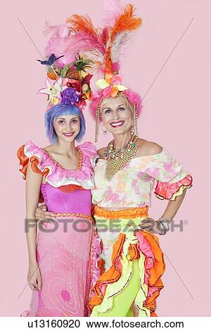 Stock Image - Portrait of happy young and senior women in Brazilian outfits over pink background. Fotosearch