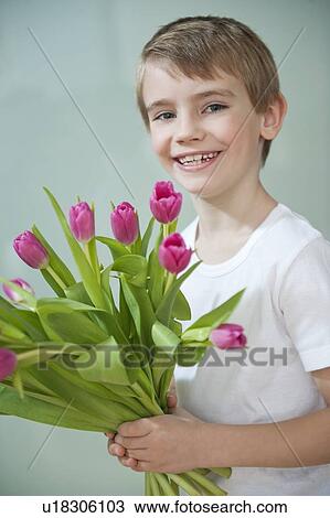 Portrait of happy young boy holding bunch of pink tulips against gray background View Large Photo Image Stock Image - Portrait of happy young boy holding bunch of pink tulips against gray background. Fotosearch