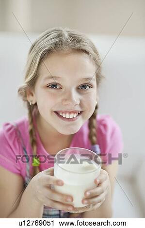 Stock Image - Portrait of happy young girl drinking milk. Fotosearch