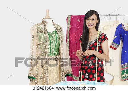 Portrait of Indian female dressmaker standing by a dummy dressed in traditional wear View Large Photo Image Picture - Portrait of Indian female dressmaker standing by a dummy dressed in traditional wear. Fotosearch
