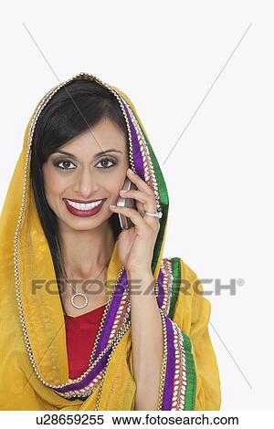 Stock Photography - Portrait of Indian woman in traditional wear attending phone call over white background. Fotosearch