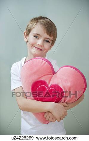Portrait of little boy holding heart shape cushion View Large Photo Image Stock Photo - Portrait of little boy holding heart shape cushion. Fotosearch