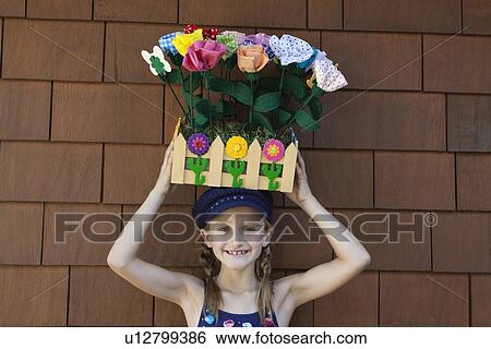 Stock Photograph - Portrait of little girl carrying artificial flowers in wooden crate on head. Fotosearch