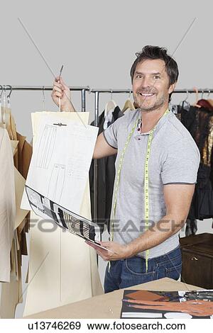Stock Photo - Portrait of male dressmaker holding sewing pattern, sketch and design draft. Fotosearch