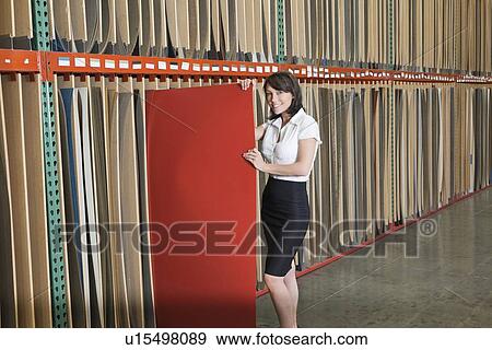 Stock Photo - Portrait of mid adult businesswoman holding thin red veneer sheet. Fotosearch