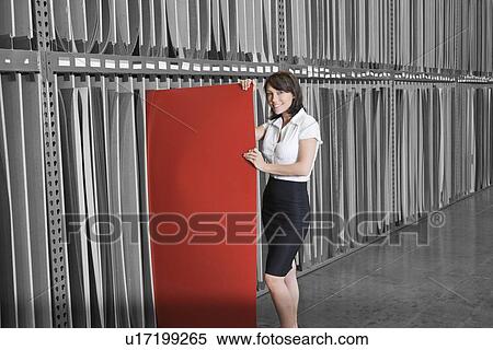 Stock Photography - Portrait of mid adult businesswoman holding thin red veneer sheet. Fotosearch