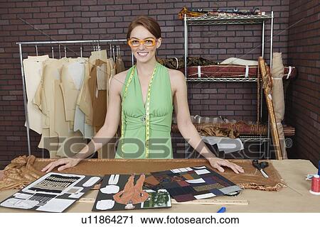 Portrait of pretty female fashion designer standing at table with layouts View Large Photo Image Stock Image - Portrait of pretty female fashion designer standing at table with layouts. Fotosearch