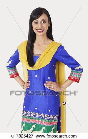 Stock Photo - Portrait of pretty Indian woman in traditional wear standing with hands on hips over gray background. Fotosearch