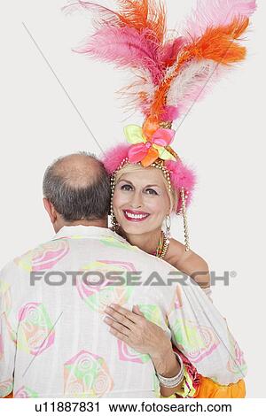 Stock Image - Portrait of senior couple in Brazilian outfits dancing over gray background. Fotosearch