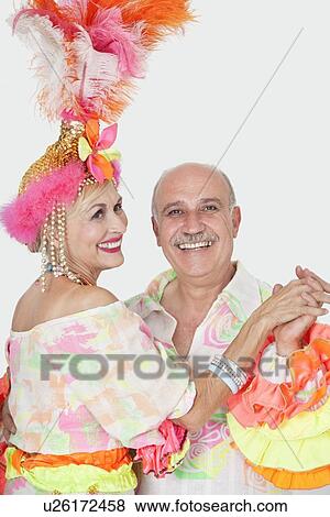 Stock Photo - Portrait of senior couple in Brazilian outfits dancing over gray background. Fotosearch
