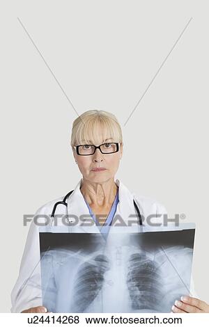 Portrait of senior female doctor with x-ray over gray background View Large Photo Image Stock Photo - Portrait of senior female doctor with x-ray over gray background. Fotosearch