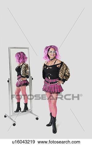 Portrait of senior female punk standing by mirror over gray background View Large Photo Image Stock Photo - Portrait of senior female punk standing by mirror over gray background. Fotosearch