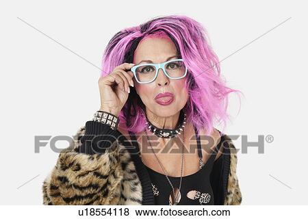 Stock Photo - Portrait of senior female punk sticking out tongue over gray background. Fotosearch
