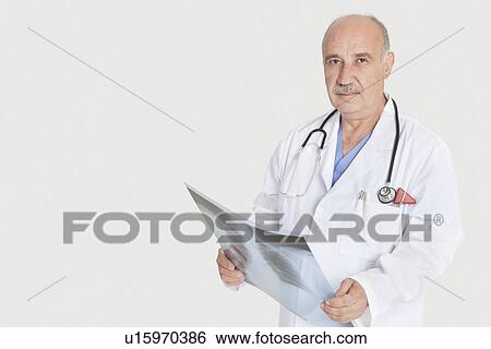 Portrait of senior male medical practitioner holding x-ray over gray background View Large Photo Image Stock Photograph - Portrait of senior male medical practitioner holding x-ray over gray background. Fotosearch