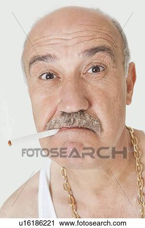 Stock Image - Portrait of senior man with cigarette in mouth over gray background. Fotosearch