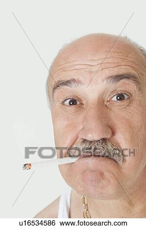 Portrait of senior man with cigarette in mouth over gray background View Large Photo Image Stock Photograph - Portrait of senior man with cigarette in mouth over gray background. Fotosearch