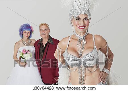Stock Photo - Portrait of senior showgirl with father and daughter in wedding dress in background. Fotosearch