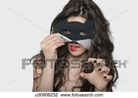 Portrait of sensuous young woman wearing cat mask while biting lip over gray background View Large Photo Image Stock Image - Portrait of sensuous young woman wearing cat mask while biting lip over gray background. Fotosearch
