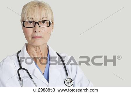 Portrait of serious female doctor with stethoscope around neck over gray background View Large Photo Image Stock Image - Portrait of serious female doctor with stethoscope around neck over gray background. Fotosearch