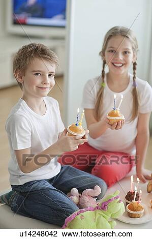 Portrait of siblings celebrating birthday with cup cakes View Large Photo Image Stock Image - Portrait of siblings celebrating birthday with cup cakes. Fotosearch