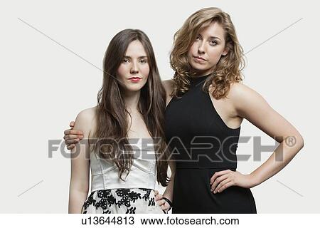 Portrait of two young female friends standing together over gray background View Large Photo Image Stock Image - Portrait of two young female friends standing together over gray background. Fotosearch