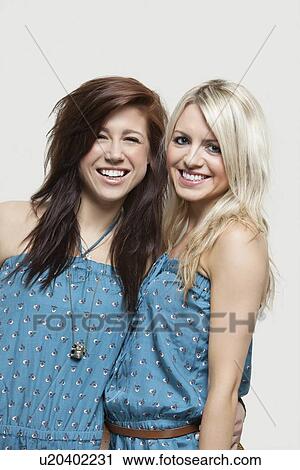 Portrait of two young women in similar jump suits smiling over gray background View Large Photo Image Stock Image - Portrait of two young women in similar jump suits smiling over gray background. Fotosearch