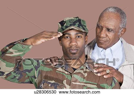 Stock Image - Portrait of US Marine Corps soldier with father saluting over brown background. Fotosearch