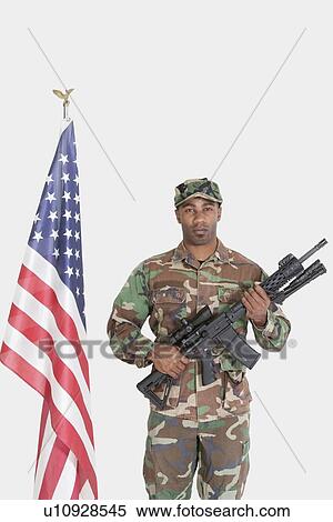 Portrait of US Marine Corps soldier with M4 assault rifle standing by American flag over gray background View Large Photo Image Stock Photography - Portrait of US Marine Corps soldier with M4 assault rifle standing by American flag over gray background. Fotosearch