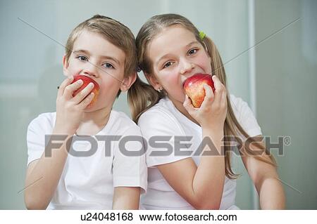 Portrait of young boy and girl in white tshirts eating apples View Large Photo Image Stock Photo - Portrait of young boy and girl in white tshirts eating apples. Fotosearch