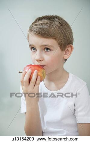 Portrait of young boy eating an apple over gray background View Large Photo Image Stock Photo - Portrait of young boy eating an apple over gray background. Fotosearch