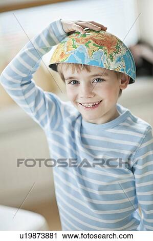 Stock Image - Portrait of young boy with world map as bowl on his head. Fotosearch