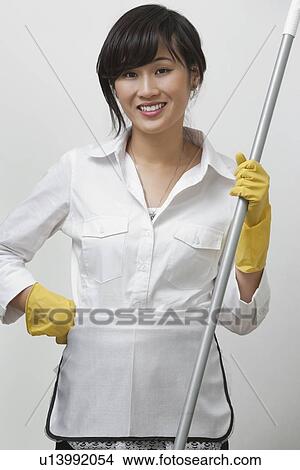 Portrait of young housemaid holding mop against gray background View Large Photo Image Picture - Portrait of young housemaid holding mop against gray background. Fotosearch