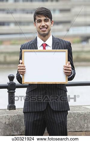 Picture - Portrait of young Indian businessman holding blank sign. Fotosearch
