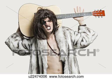 Portrait of young male musician with guitar clenching teeth over gray background View Large Photo Image Stock Photograph - Portrait of young male musician with guitar clenching teeth over gray background. Fotosearch