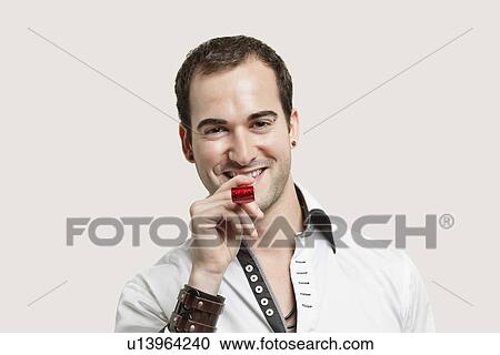 Portrait of young man blowing party puffer against gray background View Large Photo Image Stock Image - Portrait of young man blowing party puffer against gray background. Fotosearch