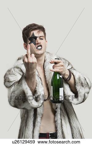 Portrait of young man with a rude gesture while holding beer bottle against gray background View Large Photo Image Stock Photo - Portrait of young man with a rude gesture while holding beer bottle against gray background. Fotosearch