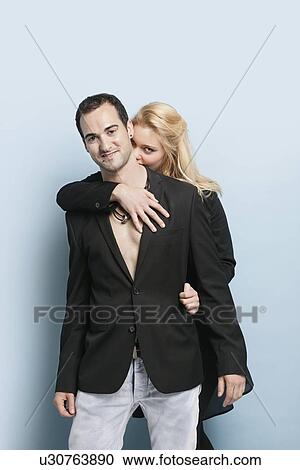 Portrait of young woman embracing man from behind against light blue background View Large Photo Image Stock Image - Portrait of young woman embracing man from behind against light blue background. Fotosearch