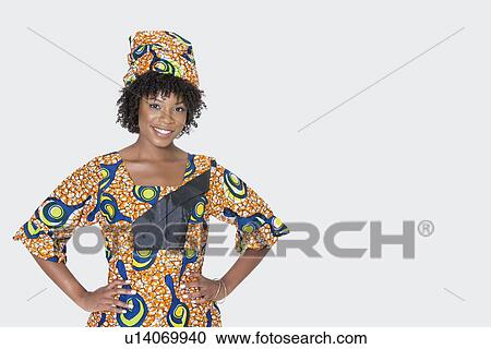 Portrait of young woman in African print attire standing with hands on hips over gray background View Large Photo Image Stock Image - Portrait of young woman in African print attire standing with hands on hips over gray background. Fotosearch
