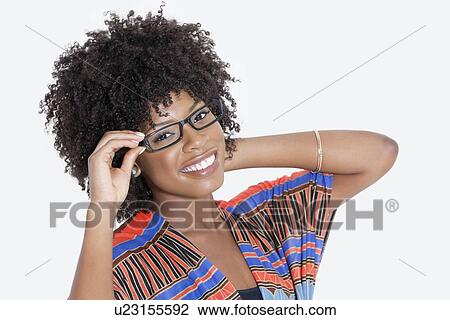 Stock Image - Portrait of young woman in African print attire wearing glasses over gray background. Fotosearch