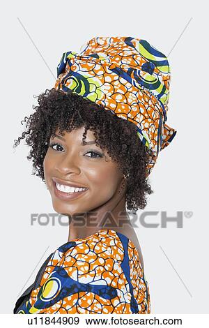 Portrait of young woman in African print attire looking over shoulder against gray background View Large Photo Image Stock Photo - Portrait of young woman in African print attire looking over shoulder against gray background. Fotosearch