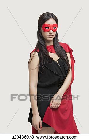 Portrait of young woman in superhero costume standing against gray background View Large Photo Image Stock Photo - Portrait of young woman in superhero costume standing against gray background. Fotosearch