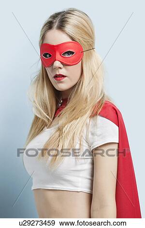 Portrait of young woman wearing superhero costume against blue background View Large Photo Image Stock Photo - Portrait of young woman wearing superhero costume against blue background. Fotosearch