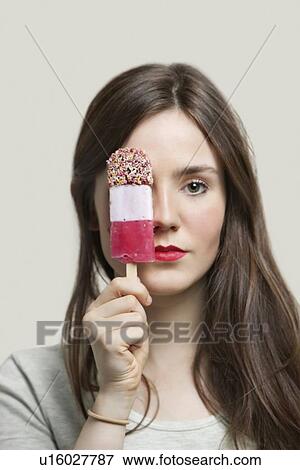 Portrait of young woman with red lips holding ice cream bar against gray background View Large Photo Image Stock Photo - Portrait of young woman with red lips holding ice cream bar against gray background. Fotosearch