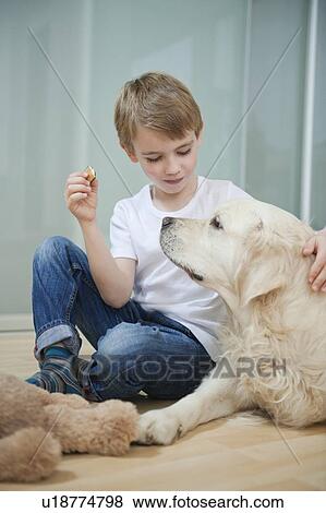 Stock Photo - Relaxed boy sitting with his dog on floor. Fotosearch